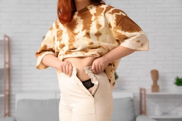 Image of woman trying to do her trousers up after pregnancy weight gain Bletchley